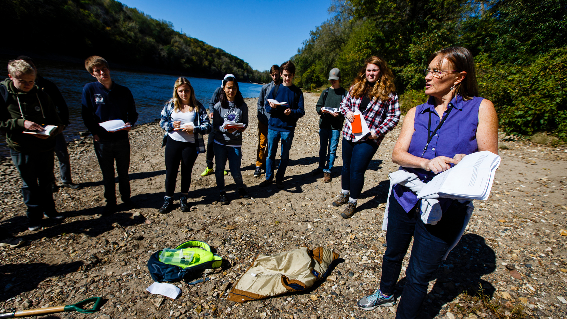 geography professor and students gather near the Mississippi River
