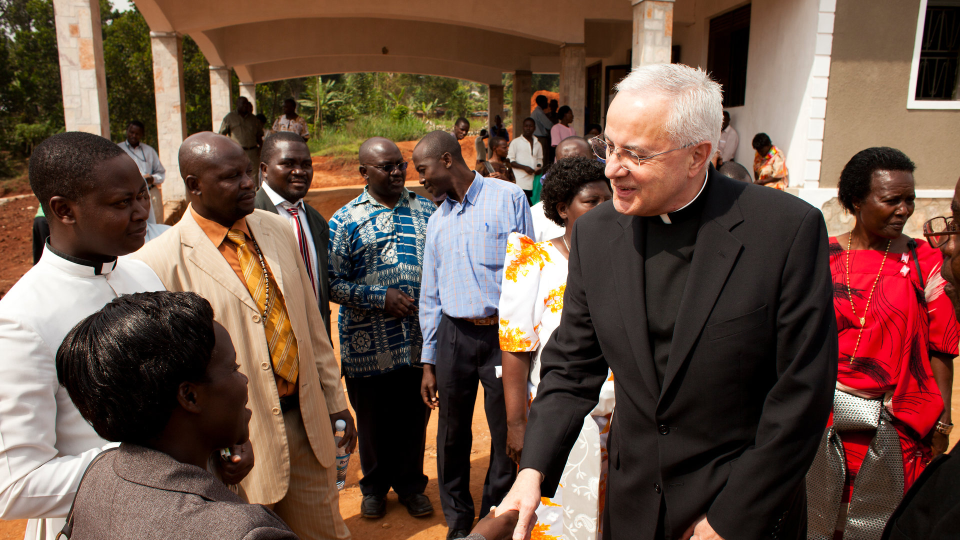 father Dennis Dease shakes hands with locals in Uganda