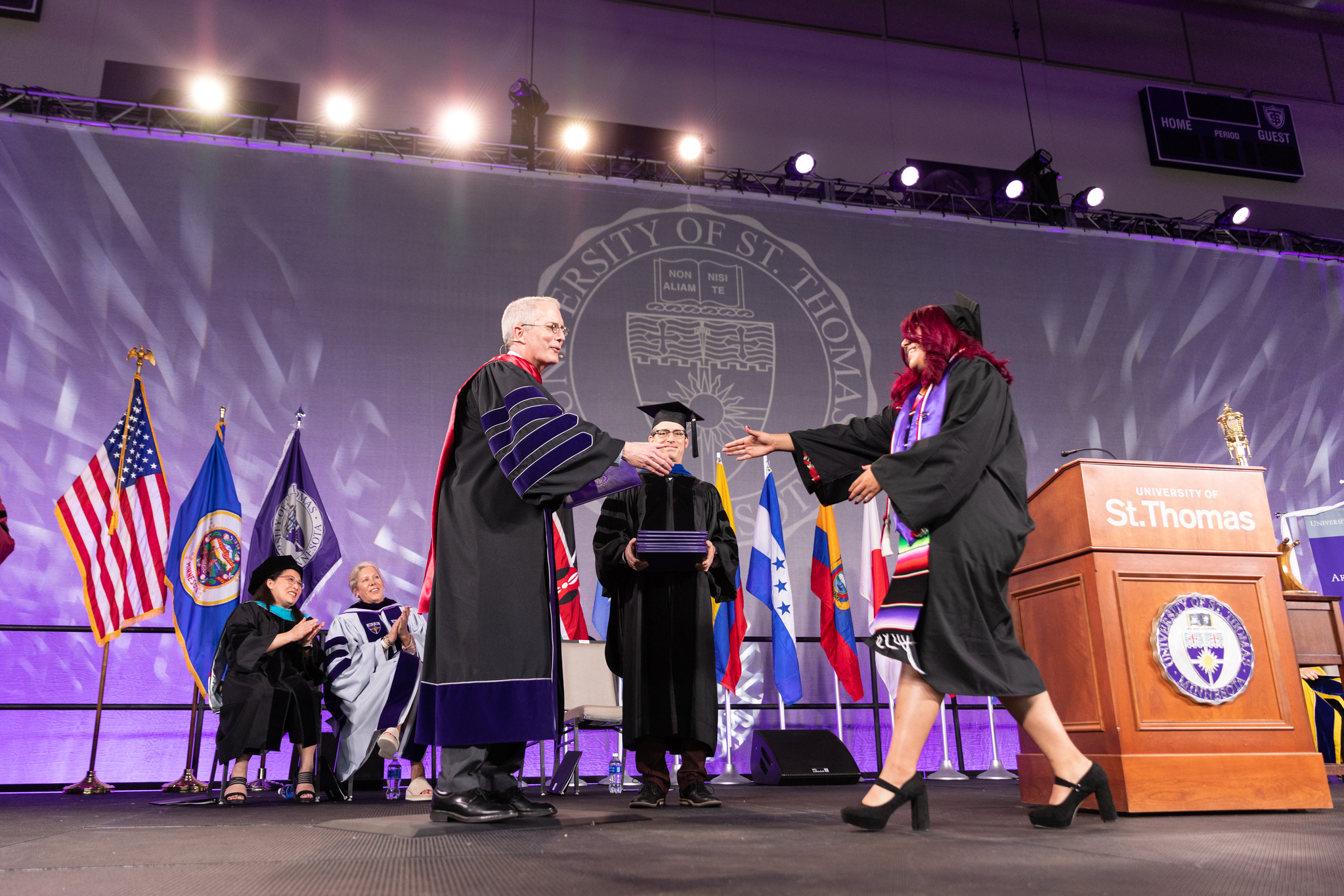 President Rob Vischer hands diploma to a student at The College of Arts and Sciences Commencement Ceremony in the AARC Field House