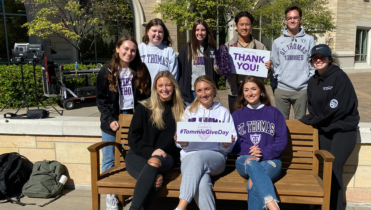 Students sitting on a bench with thank you signs