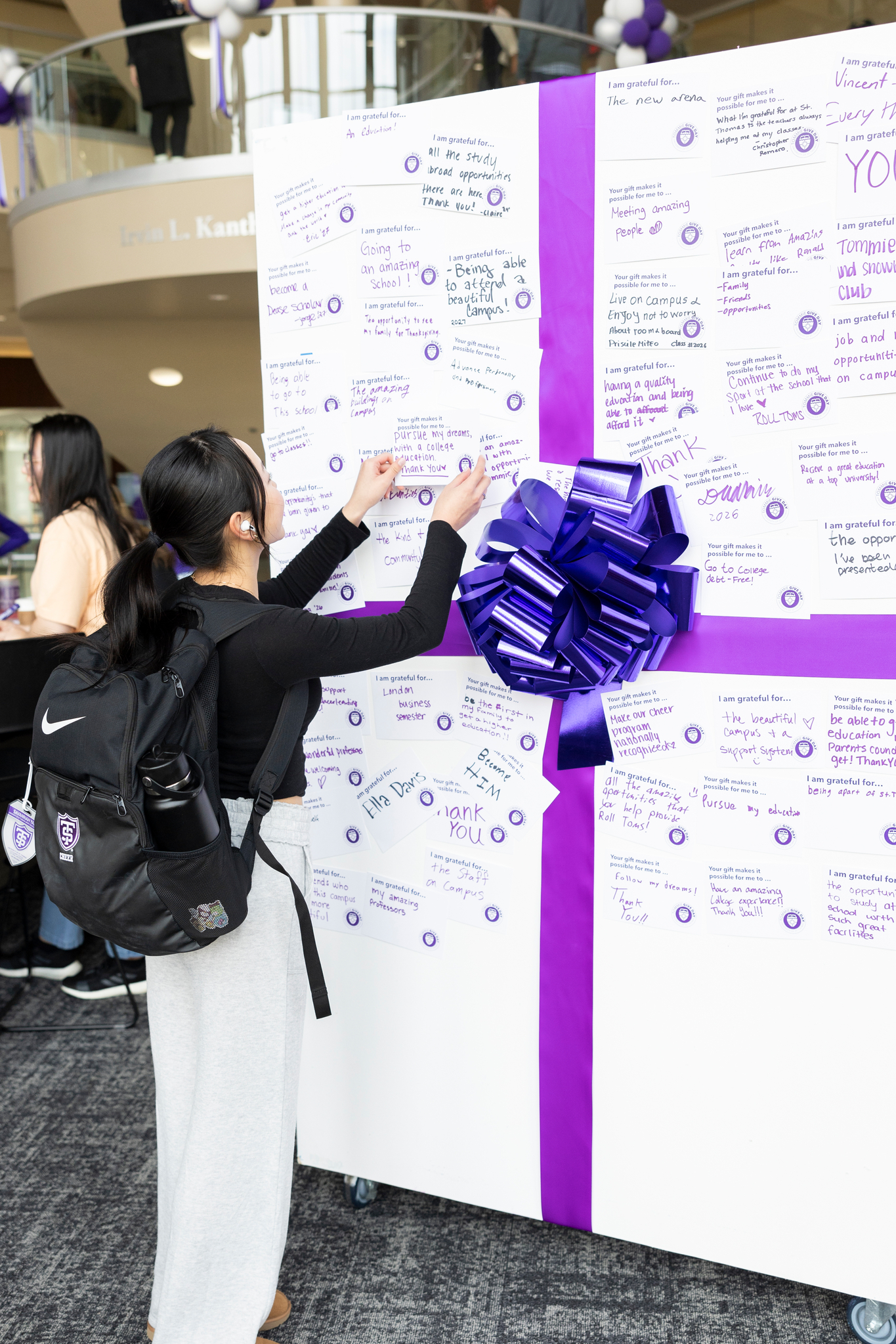 Student hanging a gratitude note on a large Tommie present