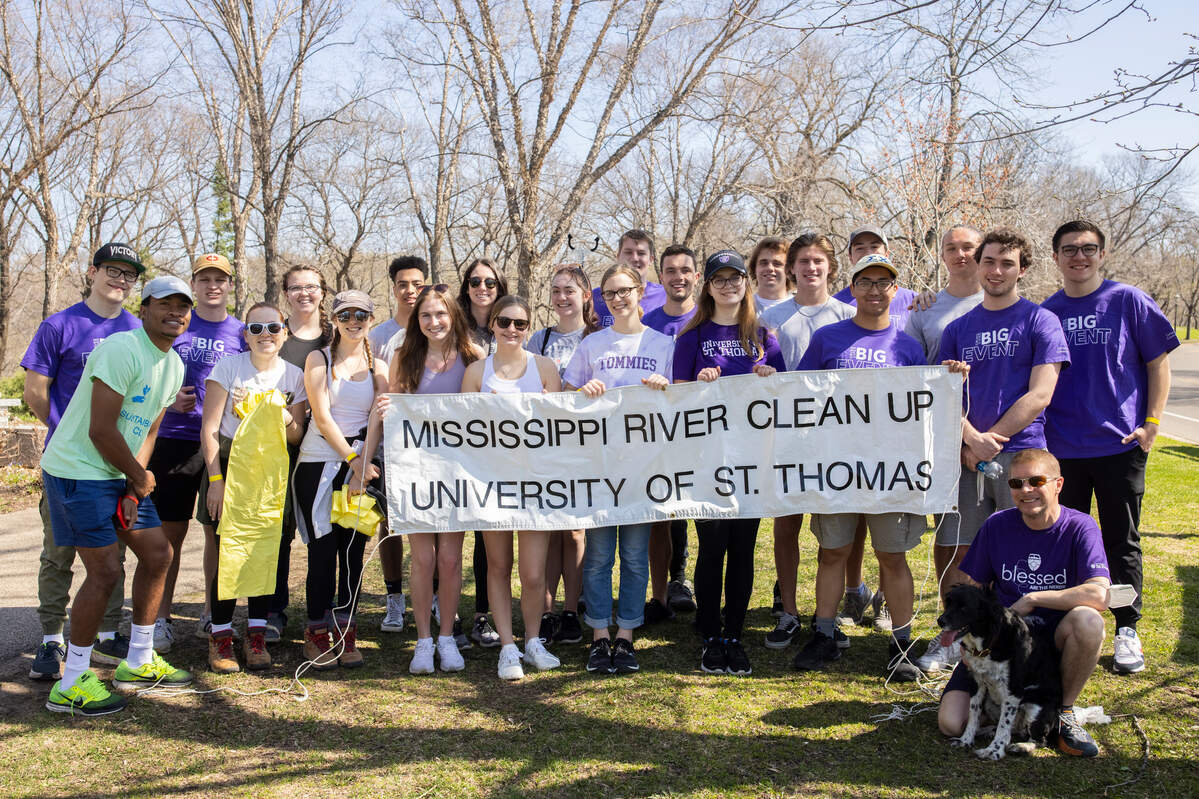 Students and alumni volunteering at a river cleanup eventt