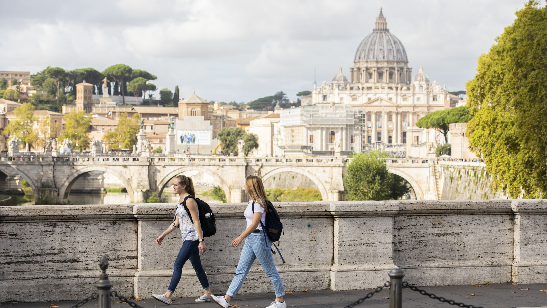 Two students walk along a street in Rome with St. Peter's Basilica in the background during a study abroad experience