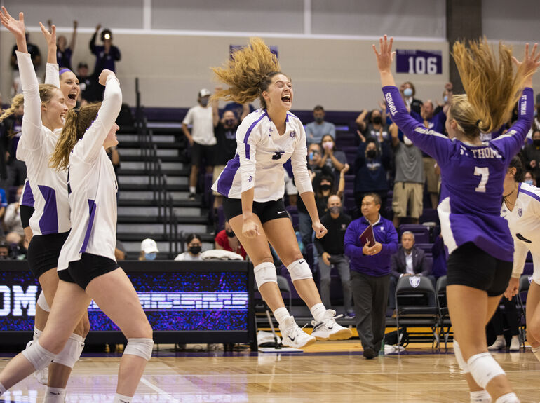A group of Volleyball athletes celebrating on the court after a point