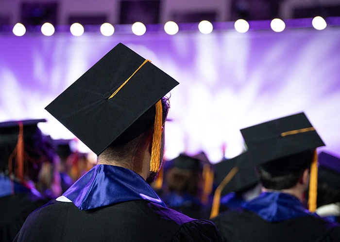 A st. Thomas graduate, wearing a mortar board, looks toward the stage where they will receive their diploma
