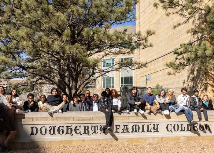 Students pose behind the Dougherty Family College stone sign