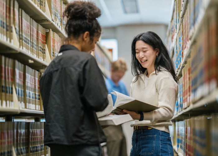 Two students laugh while selecting books in the Law Library