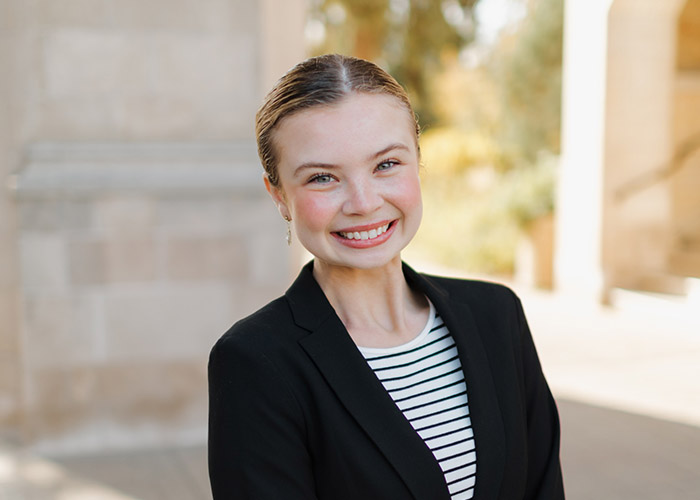 Lydia Egbers smiles into the camera for a professional portrait taken on a sunny day outside on the St. Thomas campus.