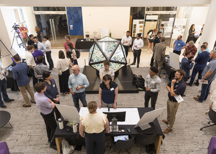 Students, faculty and guests interact around displays and exhibits inside one of the Schoenecker Center's collaborative learning spaces