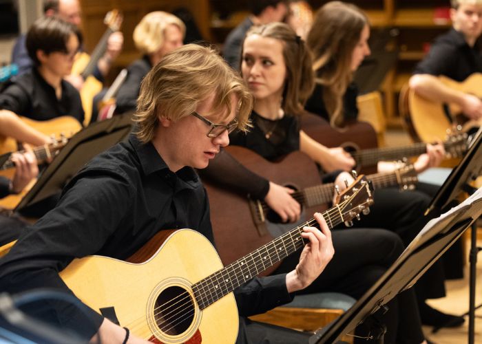 Student plays guitar during a group performance