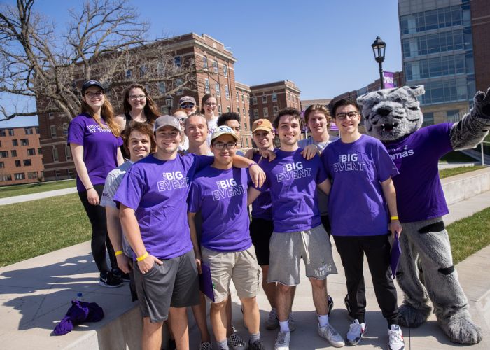 Tommie the mascot cheers with a group of students