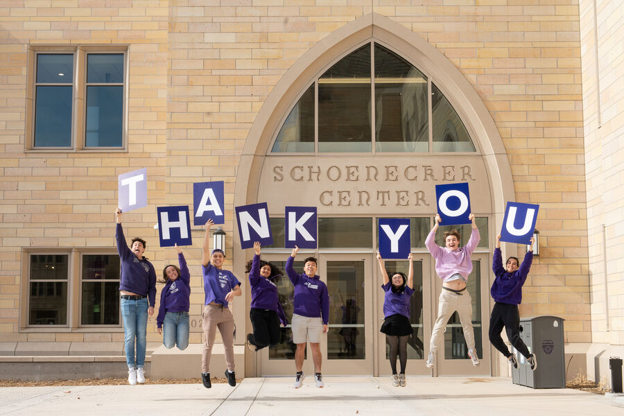 A group of St. Thomas students jumping, each one holding a letter that spells “thank you”