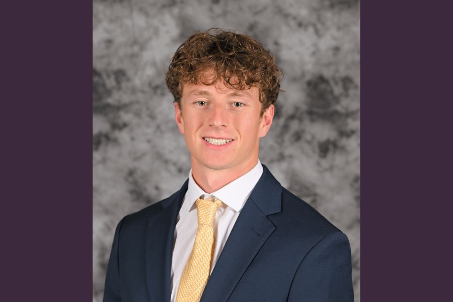 Payton smiles into the camera for a studio portrait taken in front of a grey background