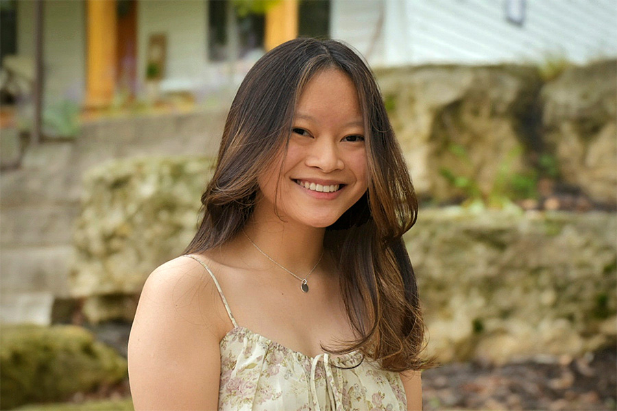Olivia smiles into the camera in front of a nature setting
