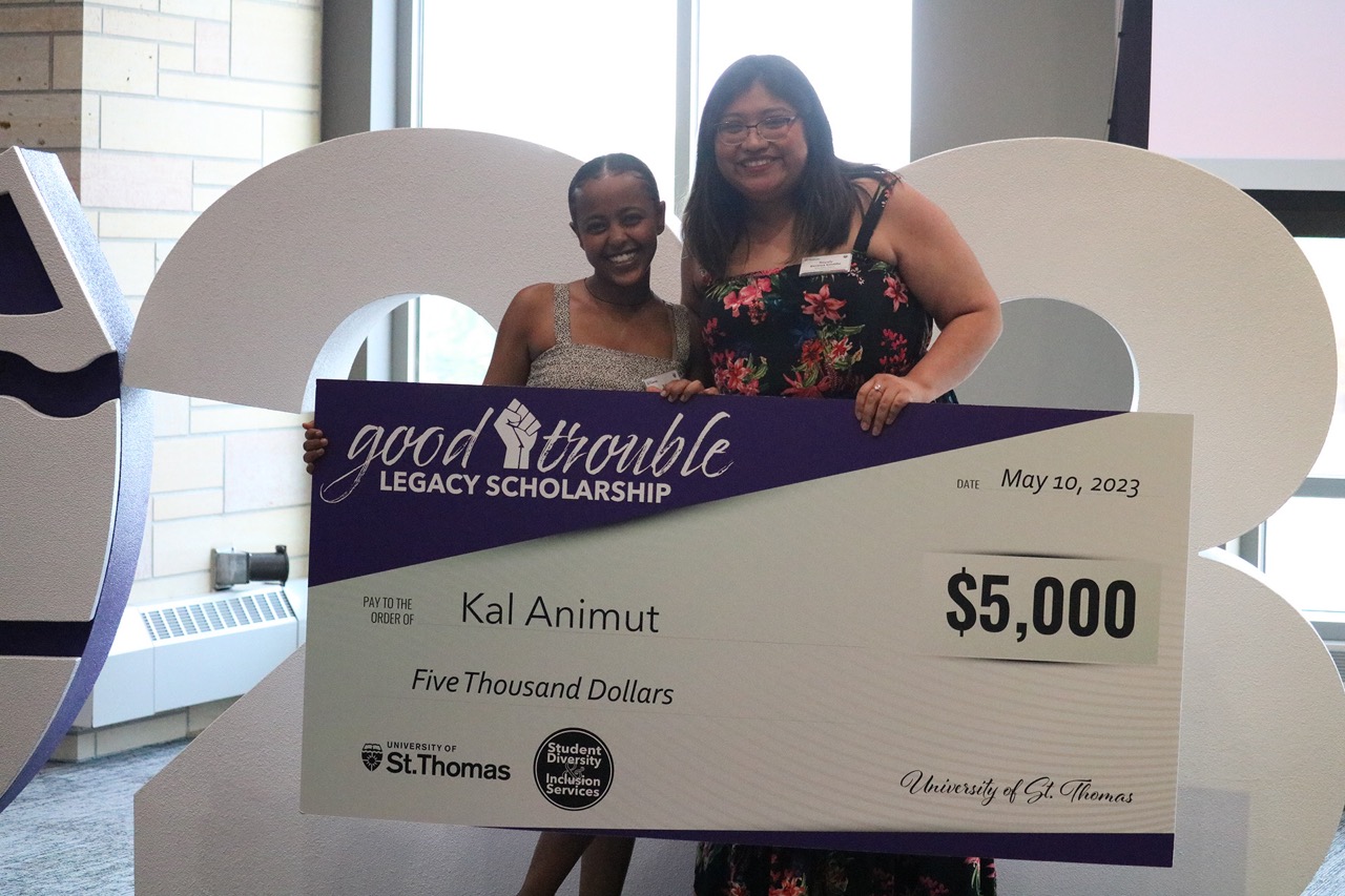 Kal Animut receives the Good Trouble Scholarship. She’s smiling and holding an oversized check written for $5,000.
