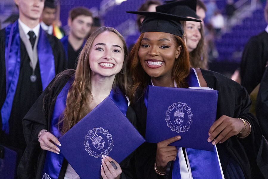 Graduates in caps and gowns proudly display their diplomas after commencement ceremony