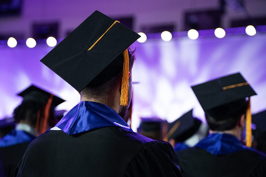 Graduating students in the caps and gowns facing the commencement stage.