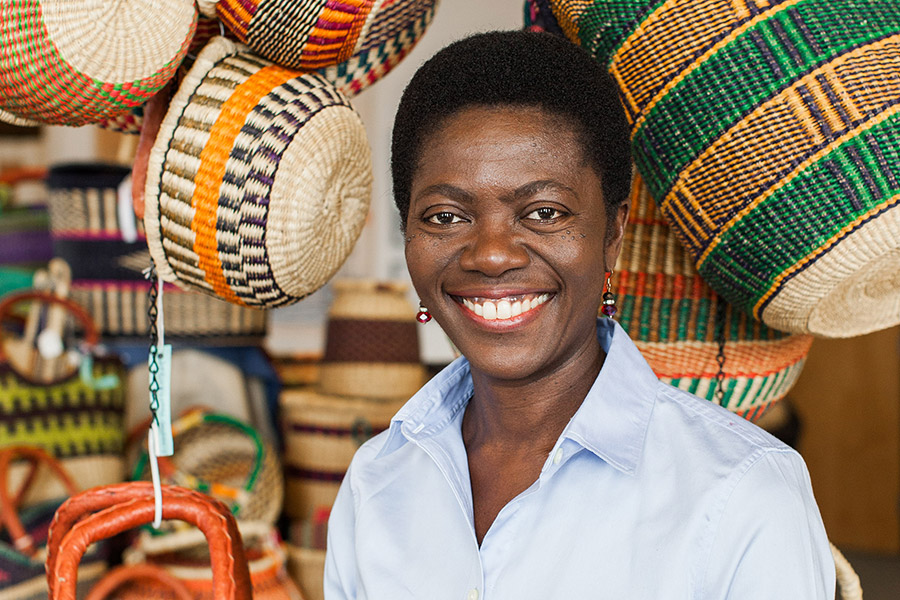 Kate Herzog smiles into the camera. She’s posing in front of a display of colorful woven baskets stacked on shelves and hanging from ropes.