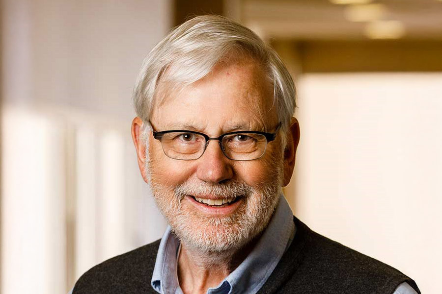 John Schweers smiles and poses for a portrait in a brightly lit office setting.