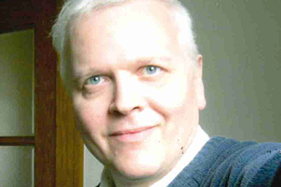Dr. Sitzmann is wearing a blue sweater and smiling in a selfie style photo
