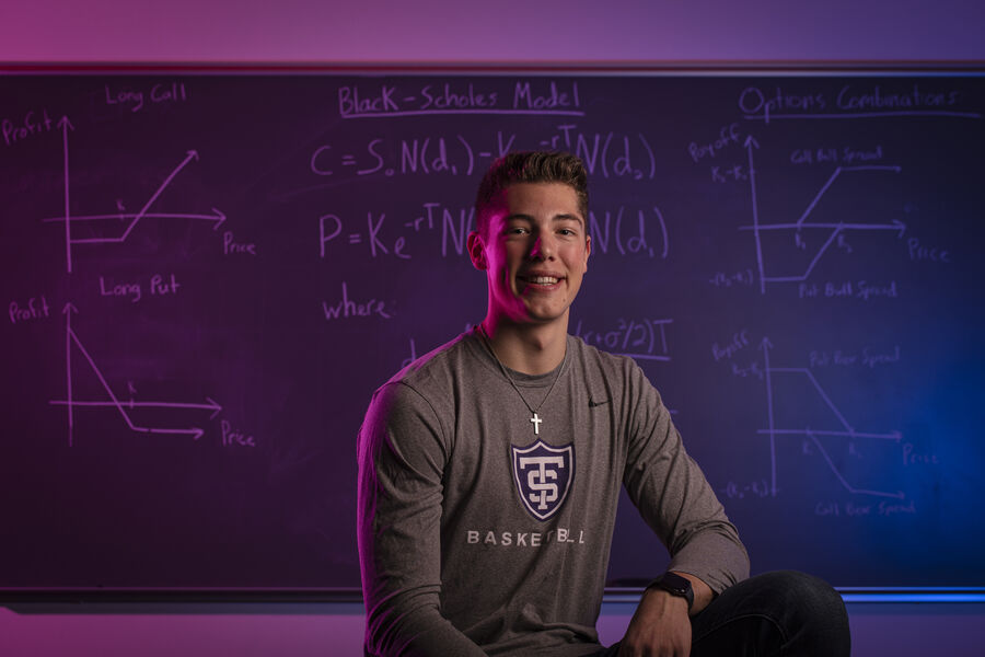 Senior Tommy Anderson, an Actuarial Science major and basketball player, poses for a photo in front of actuarial equations on a blackboard on November 4, 2019, in St. Paul.