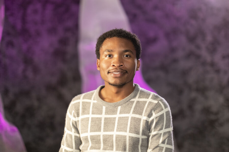 Student smiling at camera with a bright purple background
