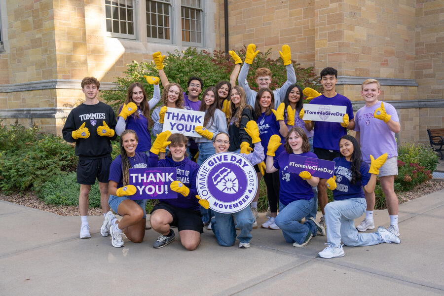 A large group of students outside the Arches holding 'thank you' signs