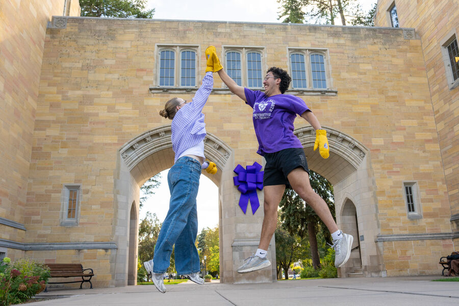 Two students jumping in front of the Arches high-fiving