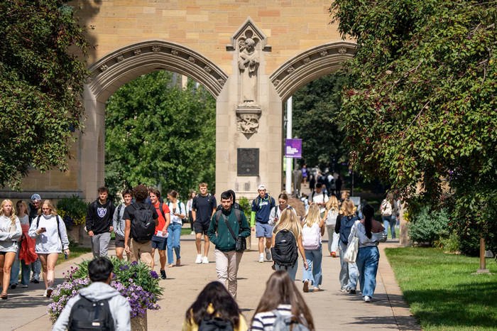 Students walking through the Arches on a sunny day