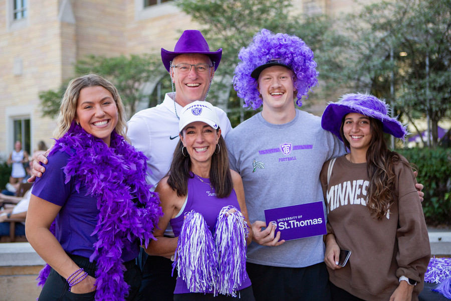 Tommie alums posing for a photo on Homecoming, wearing purple
