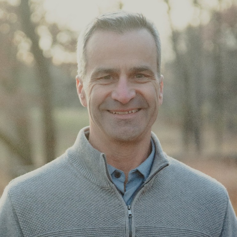 A head and shoulders photo of a man with a close-cropped haircut