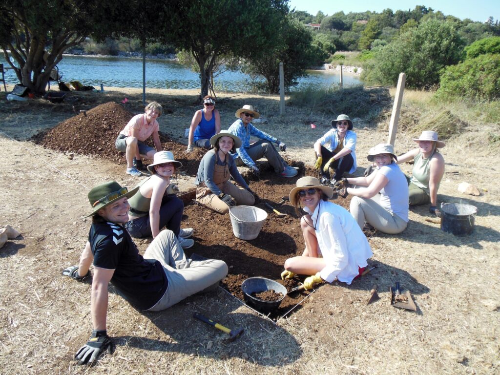 The 2022 summer St. Thomas excavation team takes a break from their work to pose for a photograph. The team spent two weeks on the island, digging, cataloguing their finds, and meeting with the local community.