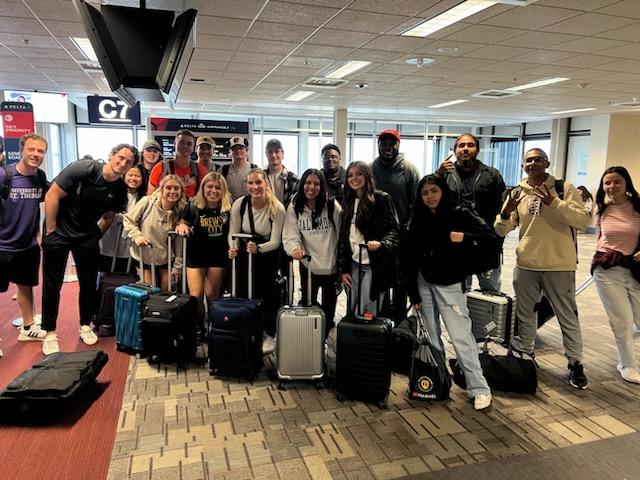 Students gathered at their airport smiling with their luggage