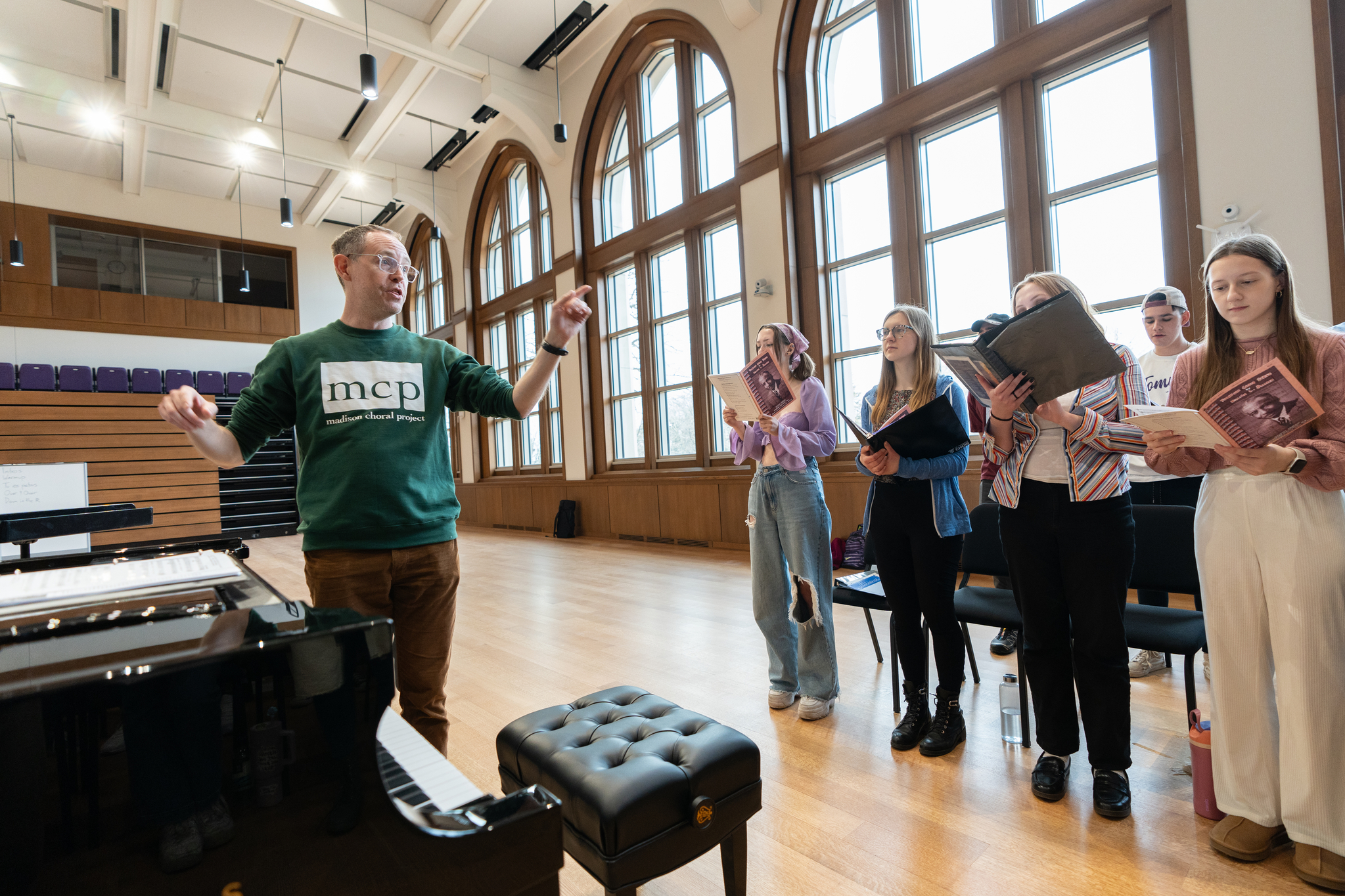 Professor leading students through the singing of a song in the performance hall